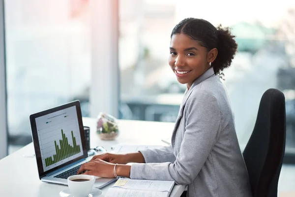Noem me maar de financiële goeroe. Foto van een jonge zakenvrouw met behulp van een laptop met grafieken erop in een modern kantoor. — Stockfoto