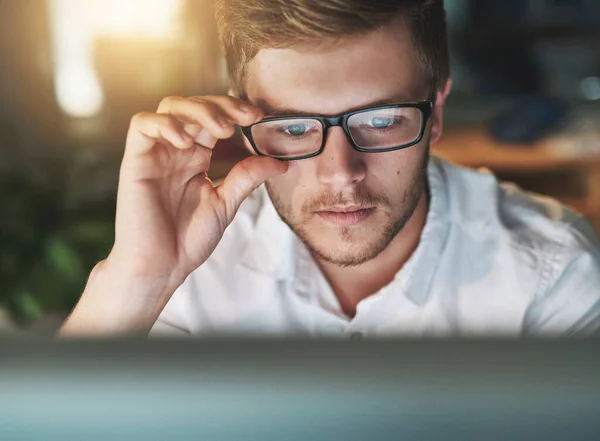 Estoy viendo esto bien. Fotografía de un joven diseñador ajustando sus gafas mientras mira la pantalla de su computadora. — Foto de Stock