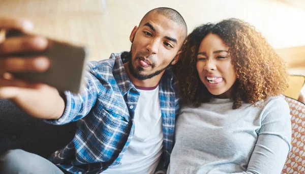 Verdadeiramente, loucamente, loucamente apaixonado. Tiro de um jovem casal feliz tirando selfies juntos em casa. — Fotografia de Stock