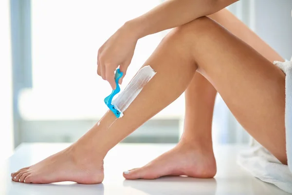 Pernas suaves ao toque. Tiro cortado de uma mulher irreconhecível raspando as pernas no banheiro em casa. — Fotografia de Stock