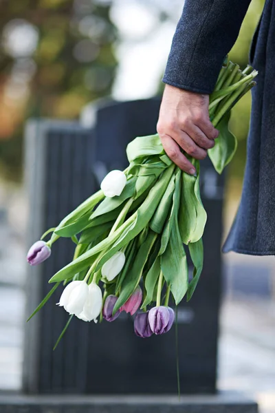 Foi-se embora, mas não foi esquecido. Tiro cortado de um homem que visita um túmulo com um monte de flores. — Fotografia de Stock