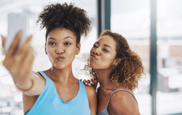 Y uno para nuestros seguidores. Fotografía recortada de dos mujeres jóvenes tomando una selfie después de la clase de yoga. — Foto de Stock