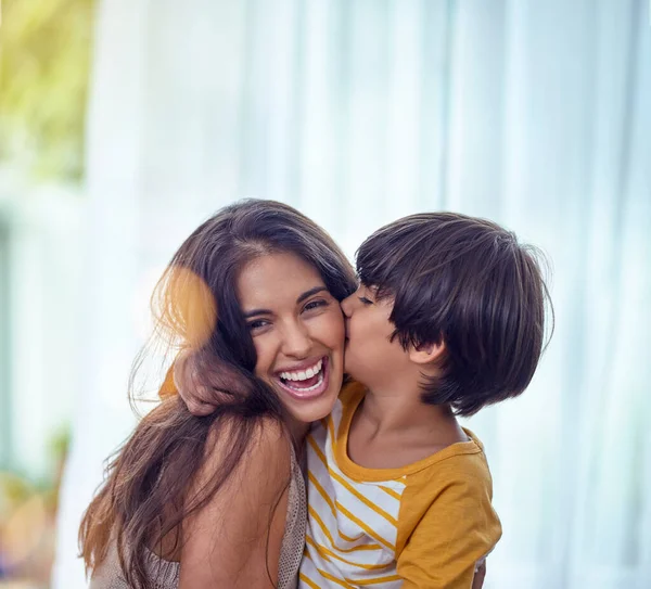 Щаслива дитина, мати якої щаслива. Знімок чарівного маленького хлопчика ласкаво цілує свою матір вдома . — стокове фото
