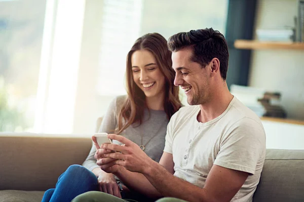 Condividere e 'affettuoso. Girato di una giovane coppia felice utilizzando un telefono insieme sul divano di casa. — Foto Stock