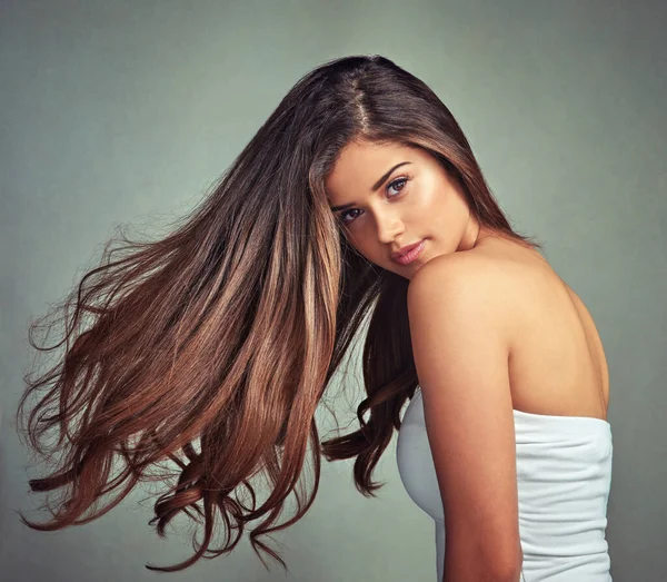 Natuurlijke schoonheid is ware schoonheid. Studio portret van een mooie vrouw met lange lokken poseren tegen een grijze achtergrond. — Stockfoto