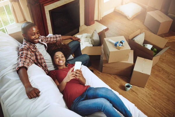 Who should we invite to the housewarming. Shot of a young couple taking a break while moving into their new home. — Stock Photo, Image