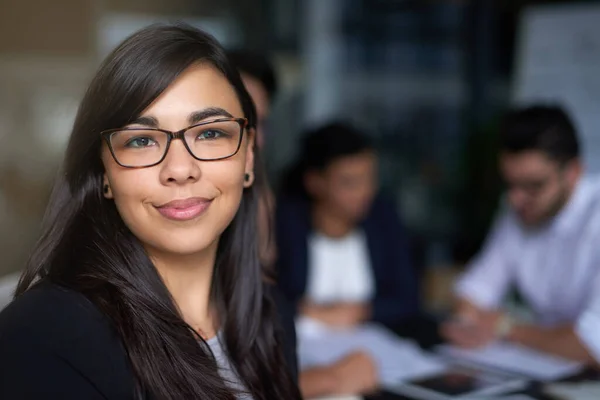 Shes a standout in the office. Portrait of a smiling young businesswoman in an office with colleagues in the background. — Stock Photo, Image