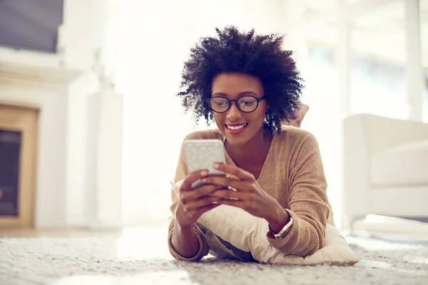 Mantendo seu telefone fresco com alguns aplicativos novos. Tiro de uma jovem mulher usando seu telefone em casa. — Fotografia de Stock
