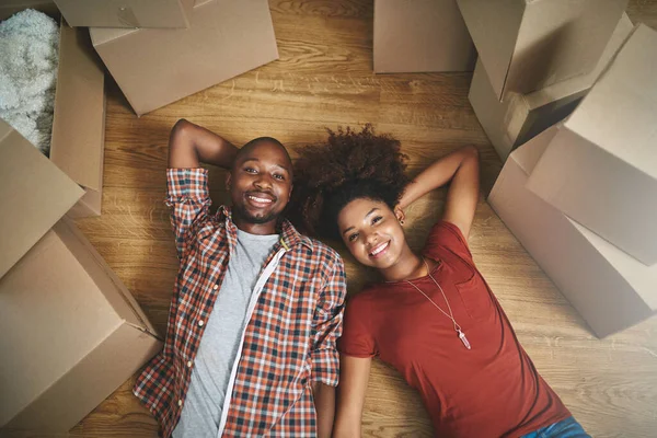 Glad to be sharing this milestone together. High angle shot of a young couple taking a break while moving into their new home. — Stock Photo, Image