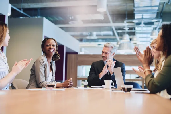 Buen trabajo. Fotografía de bajo ángulo de un grupo de empresarios aplaudiendo a un colega mientras se sienta en la sala de juntas durante una reunión. —  Fotos de Stock