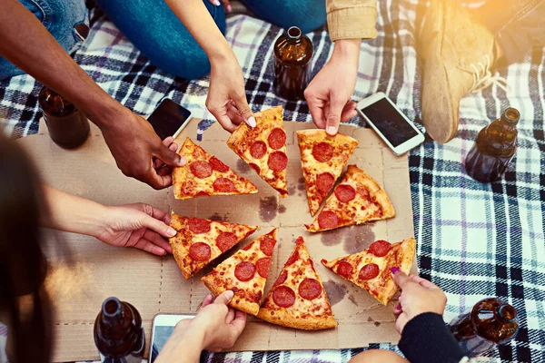 피자는 최고의 피크닉을 만듭니다. 피크닉을 하고 있는 친구들 이 피자를 먹는 장면이 걸려 있다. — 스톡 사진