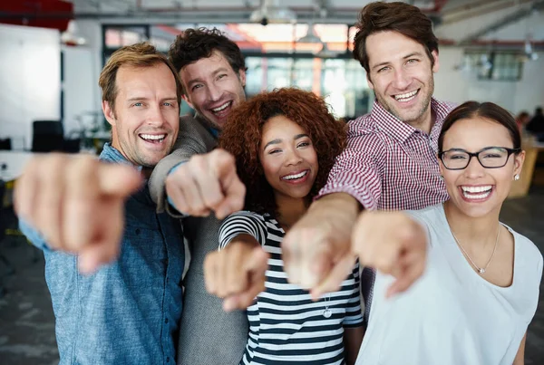 Ons team wil jou. Portret van een groep lachende collega 's die naar de camera wijzen terwijl ze in een kantoor staan. — Stockfoto