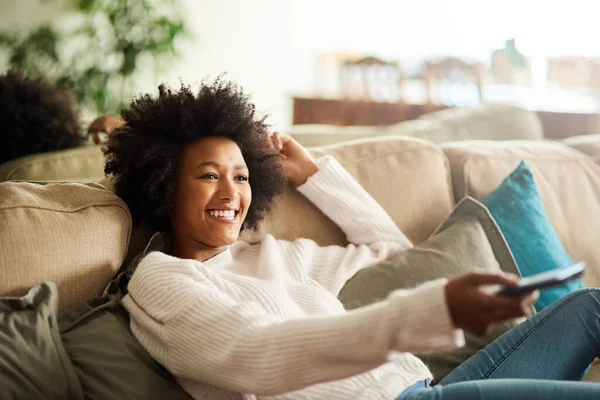 De licença até nova ordem. Tiro de uma jovem mulher relaxando no sofá em casa e assistindo TV. — Fotografia de Stock
