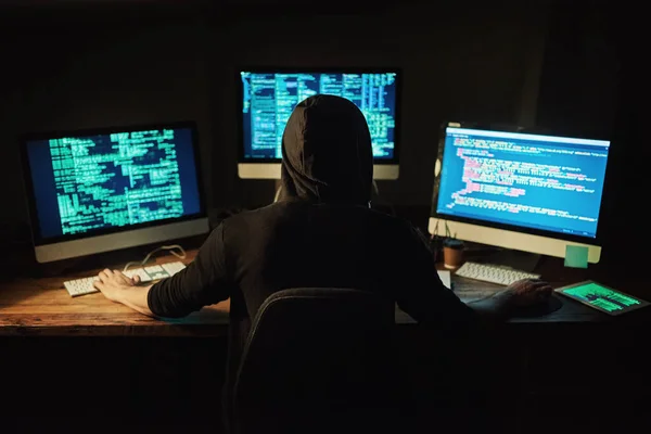 De code ontrafelen. Achteraanzicht shot van een jonge hacker kraken van een computer code in het donker. — Stockfoto