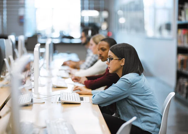 Travailler dur pour accomplir toutes leurs tâches. Prise de vue d'un groupe d'étudiants universitaires travaillant sur des ordinateurs dans la bibliothèque du campus. — Photo