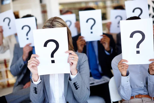 Dont be afraid to own your voice. Shot of a group of businesspeople holding up signs with question marks on them during a work presentation. — Stock Photo, Image