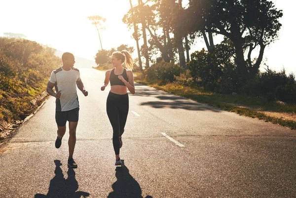 Nechat proudit krev s kamarádem na cvičení. Shot of a fit young couple going to a run outdoors. — Stock fotografie
