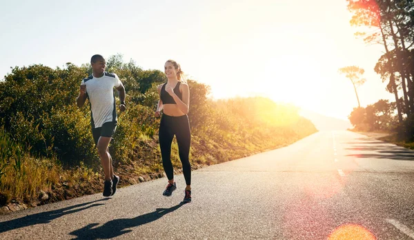 Corriendo por el camino abierto. Tiro de una pareja joven en forma que va a correr al aire libre. —  Fotos de Stock