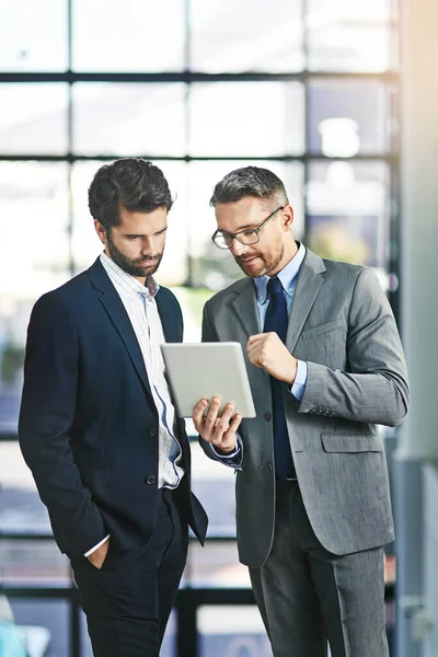 Encontrar maneiras de deixar seu negócio prosperar ainda mais. Foto cortada de dois empresários trabalhando juntos em um tablet digital em um escritório. — Fotografia de Stock