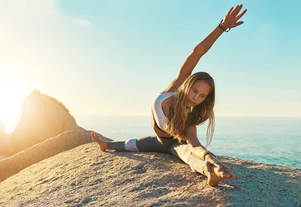 Fais-leur se demander pourquoi tu brilles. Prise de vue d'une jeune femme sportive pratiquant le yoga sur la plage. — Photo