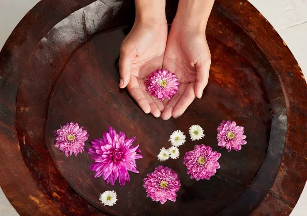 Soaking up at the spa. Cropped shot of a womans hands in a flower filled water bowl at a spa. — Stock Photo, Image