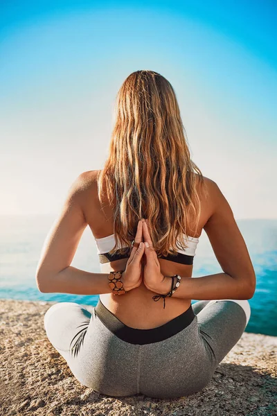 C'est le moment de pratiquer le yoga. Vue arrière d'une jeune femme pratiquant le yoga sur la plage. — Photo
