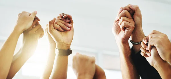 Were stand strong and tall. Closeup shot of a group of unrecognizable businesspeople holding hands while raising their arms. — Stock Photo, Image