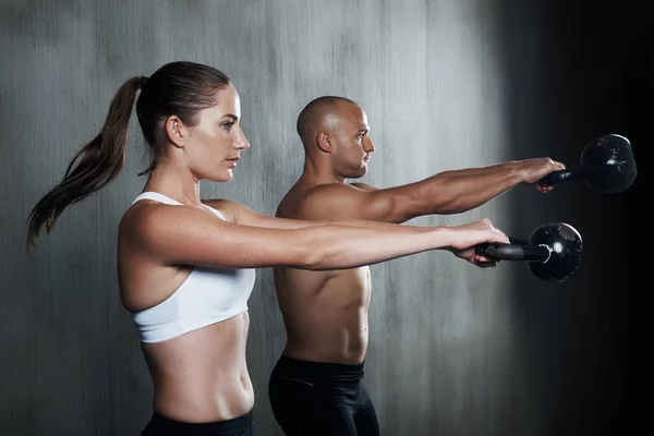 Entrenamiento para convertirse en combate en forma. Un hombre y una mujer haciendo ejercicio con campanas de caldera en el gimnasio. —  Fotos de Stock