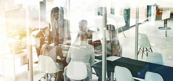 Getting down to business in the city. Multiple exposure shot of businesspeople in an office superimposed on a cityscape. — Stock Photo, Image