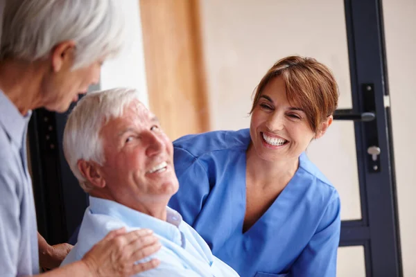 Recibir la mejor atención disponible. Recorte de una enfermera de pie junto a su paciente mayor y su esposa. —  Fotos de Stock