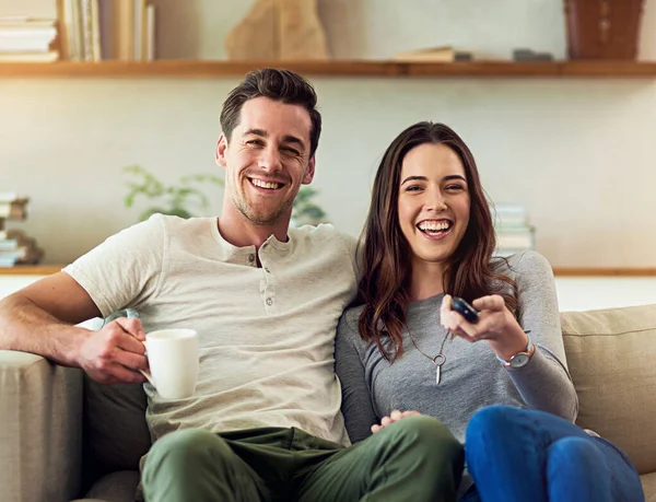 Non perdiamo mai un episodio. Ritratto di una giovane coppia felice che si rilassa sul divano e guarda la tv insieme. — Foto Stock