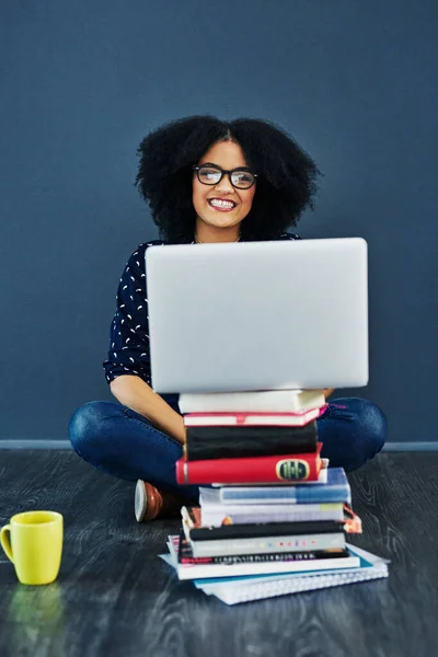 Знання є найкращим інструментом. Студійний знімок молодої жінки за допомогою ноутбука з книгами, що стоять перед нею на синьому фоні . — стокове фото