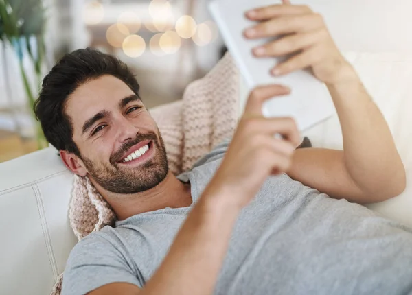 Faules Wochenende online. Aufnahme eines jungen Mannes, der zu Hause auf einem digitalen Tablet im Internet surft. — Stockfoto