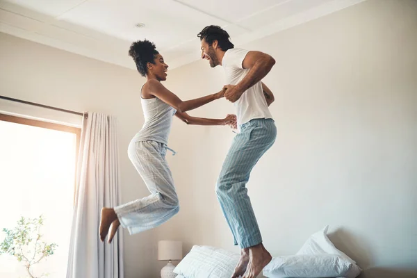 Theres so much fun in this relationship. Full length shot of an affectionate young couple jumping playfully on their bed at home. — Stock Photo, Image