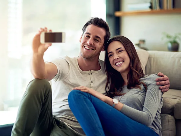 Felice a casa con il mio amore. Girato di una giovane coppia felice scattare selfie insieme a casa. — Foto Stock