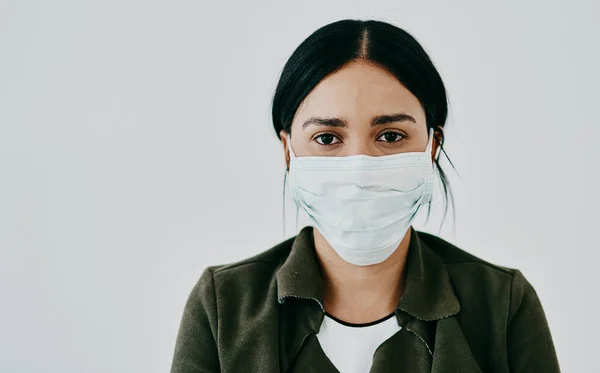 Fica em casa e pára a propagação. Retrato de uma jovem mulher usando uma máscara contra um fundo de estúdio cinza. — Fotografia de Stock