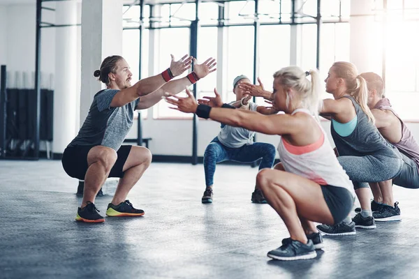 Er ist derjenige, der Sie in Form bringt. Aufnahme eines Fitnesstrainers, der mit einer Gruppe von Menschen im Fitnessstudio arbeitet. — Stockfoto