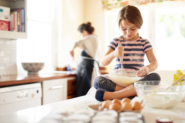 C'est une grande assistante dans la cuisine. Tourné d'une petite fille aidant sa mère à cuire dans la cuisine. — Photo