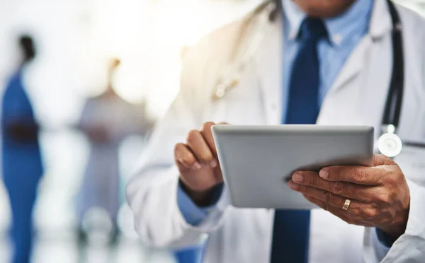 Seine Patienten mit drahtloser Technik in seiner Nähe zu halten. Schnappschuss eines Arztes mit einem digitalen Tablet und seinen Kollegen im Hintergrund. — Stockfoto