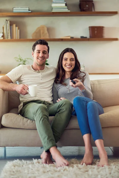 Cita de cine en el frente de casa. Retrato de una feliz pareja joven relajándose en el sofá y viendo la televisión juntos. — Foto de Stock