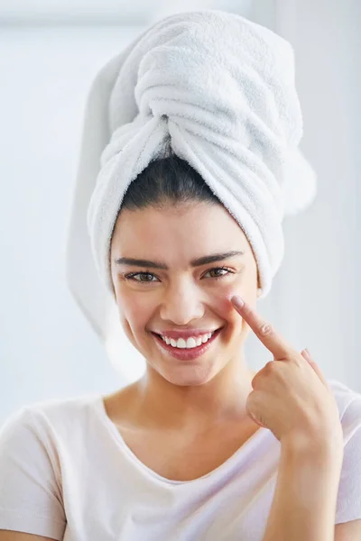 Give your skin the moisture it needs. Portrait of a beautiful young woman applying moisturizer to her skin in the bathroom at home. — Stock Photo, Image