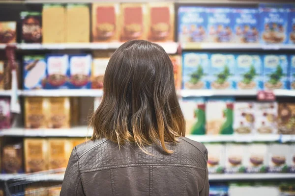 何を買えば？。食料品店で買い物中の若い女性のレビューショット. — ストック写真