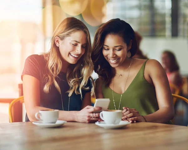 Café y amigos, es mejor cuando los pones juntos. Recorte de novias compartiendo algo en un teléfono celular mientras está sentado en un café. —  Fotos de Stock