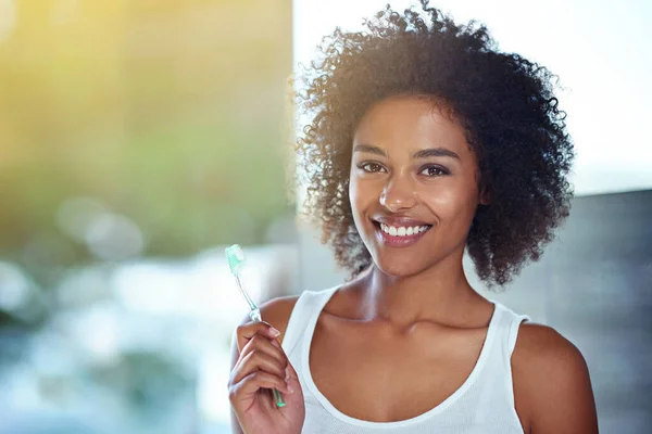 Jobbar för det vinnande leendet. Beskärda porträtt av en ung kvinna borsta tänderna i badrummet. — Stockfoto