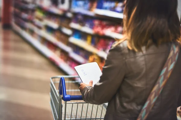 The pro di belanja grosir. Foto seorang wanita sedang berbelanja dengan sebuah daftar di sebuah toko kelontong. — Stok Foto
