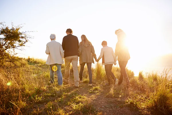Kráčím ve zlatém odpoledni. Zadní snímek multigenerační rodiny kráčející společně při západu slunce. — Stock fotografie