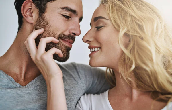 ¿Qué tal un beso? Foto de una joven pareja disfrutando de un momento relajante y romántico en casa. —  Fotos de Stock