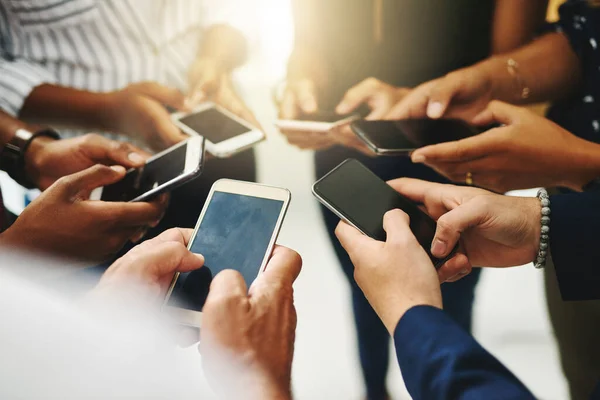 Det finns inget snabbare sätt att sprida ordet än online. Närbild skott av en grupp oigenkännliga företagare som använder sina mobiltelefoner i synkronisering. — Stockfoto