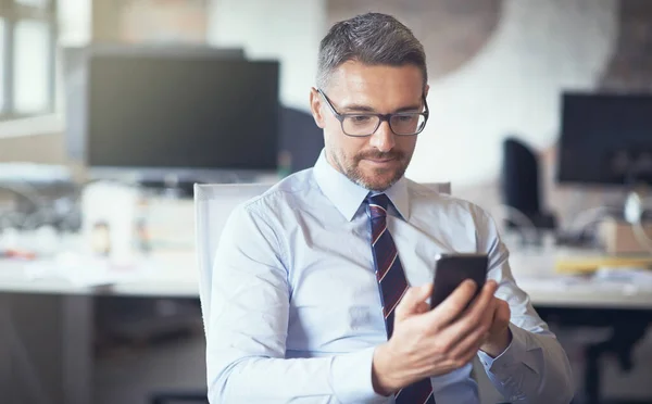 E enviar... foto cortada de um homem de negócios usando seu celular enquanto sentado em seu escritório. — Fotografia de Stock