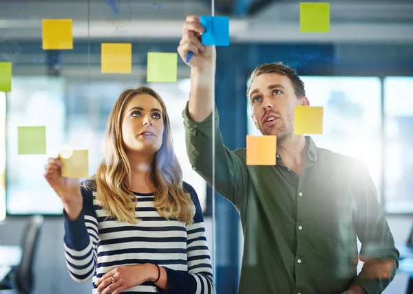 Asking the right questions to get the right answers. Shot of colleagues having a brainstorming session with sticky notes at work. — Stock Photo, Image